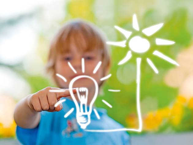 Erneuerbare Energien Anlagen, Ein Junge malt eine Sonne, die mit einer Glühbirne verbunden ist.