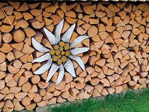 "Intarsienarbeit", wie das Edelweiß, steigert den dekorativen Wert eines Holzstapels ebenfalls.
