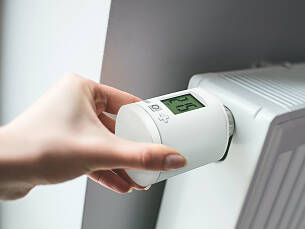Ein programmierbares Thermostat misst die Raumtemperatur und steuert das Heizkörperventil automatisch.