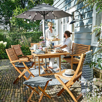 Der Sonnenschirm „Siesta“ von Butlers spendet tagsüber angenehmen Schatten und erhellt abends mit einer Lichterkette den Sitzplatz.